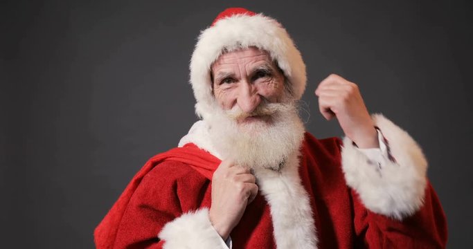 Joyful santa claus touches white moustache on his way to childrens' homes, isolated indoor shoot
