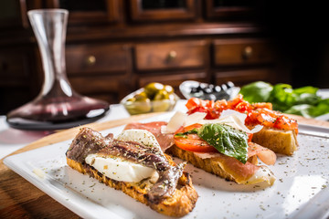 Tasty italian appetizer bruschettes with tomatoes anchovies prosciutto and mozarella