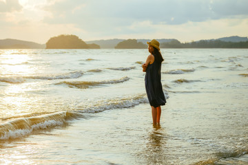 Fototapeta na wymiar single girl enjoys herself standing on beach during sunset, photo taken on Ao Nang beach, Krabi, Thailand.