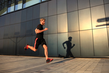Fototapeta na wymiar Sporty young man running outdoors to stay healthy, at sunset or sunrise. Runner.