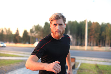Fototapeta premium Fit athlete. Handsome adult man running outdoors to stay healthy, at sunset or sunrise. Runner.