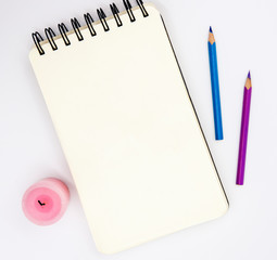 Blank sketchbook, pink violet pencils, pink candle on white background. Artistic table top view photo.