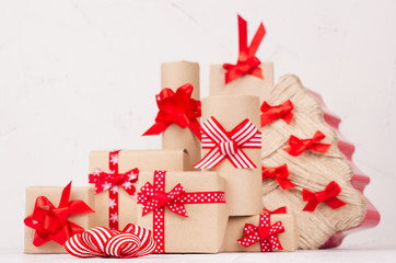 New Year festive background - kraft gift boxes with red bows and ribbons and christmas tree on white wood board.