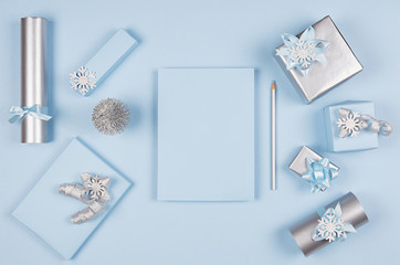 Ideas for design christmas decorations and plank paper as wishlist - soft light pastel blue and silver metallic gift boxes and glitter christmas tree with copy space, top view.