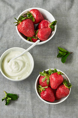 Fresh juicy organic red strawberries in white bowls and sour cream.Top view.Flat lay