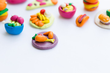 Miniature play dough burgers, hot dog, french fries, chicken thigh on white isolated background, unhealthy fast food school meal concept, artificial or plastic modern colorful dyed food, copy space  