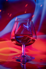 Two glasses of alcohol with ice on a colored background