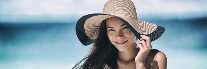 Beach sun tan skin care Asian beauty woman happy on beach vacation panoramic banner wearing sunhat....