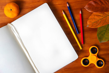 Blank page of sketchbook and autumn props on wooden background. Open sketch book top view.