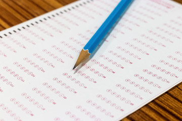 Blue pencil on paper computer sheet. Standardized test form with answers bubble. Multiple choice answer sheets. Ideas about education.