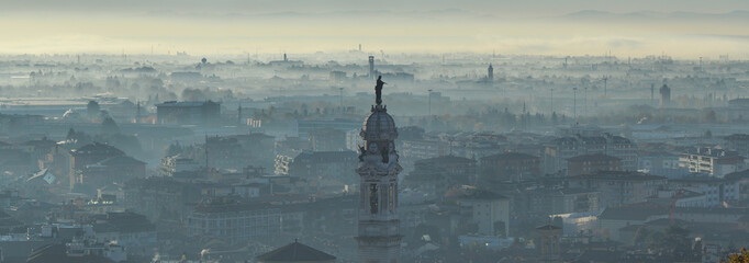 Fototapeta na wymiar Bergamo, Italy. Amazing landscape of the town covered by the fog arising from the plain in fall season
