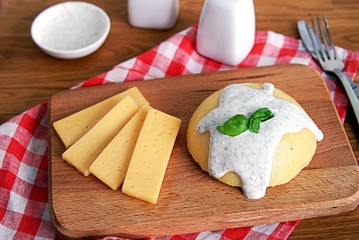 Polenta or hominy, a dish of corn grits or corn flour on a brown background. Served with sour cream and mint sauce.