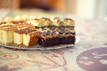Platter with homemade cakes on a table covered with a tablecloth.