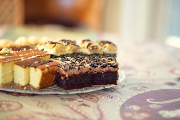 Platter with homemade cakes on a table covered with a tablecloth.