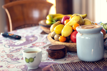 Table covered with a tablecloth and fruit on dishes in it. Shallow depth of field.