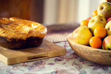 Table covered with a tablecloth and fruit on dishes and a baked cake on it. Shallow depth of field.
