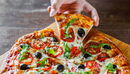 woman Hand takes a slice of Pizza Margherita or Margarita with Mozzarella cheese, tomato, olive....