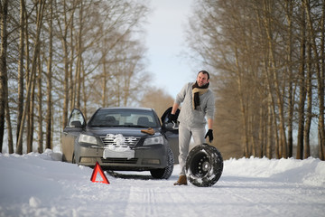 A man near a broken car on a winter day
