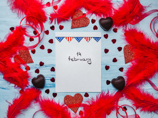 Note with sweet words of love, ribbons, colorful feathers, candy and tinsel in the shape of a heart. Top view, isolated background. Congratulations for loved ones, relatives, friends and colleagues