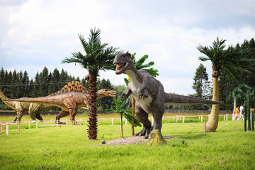 Park of dinosaurs. A dinosaur on the background of nature. Toy dinosaurs in the amusement park.
