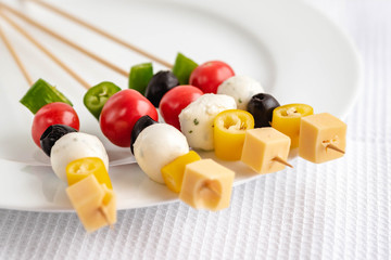 Appetizer on stick with various vegetables and cheese.