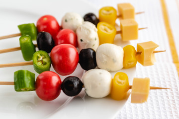 Appetizer on stick with various vegetables and cheese.