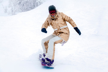 Fototapeta na wymiar Professional woman snowboarder in golden sportswear riding on slope in snowy sunny high mountains. Blur, soft focus, object in motion. Concept of freeride