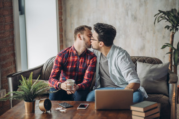 Happy same-sex couple sharing special moment of love. Lover man surprising his boyfriend with a...