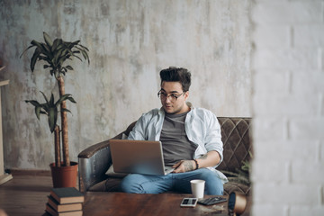 Bearded Hipster working Laptop modern Interior Design Loft Office.Man work Retro Sofa,Use contemporary Notebook,typing message.Blurred Background.Creative Business Startup Idea.Horizontal,Film