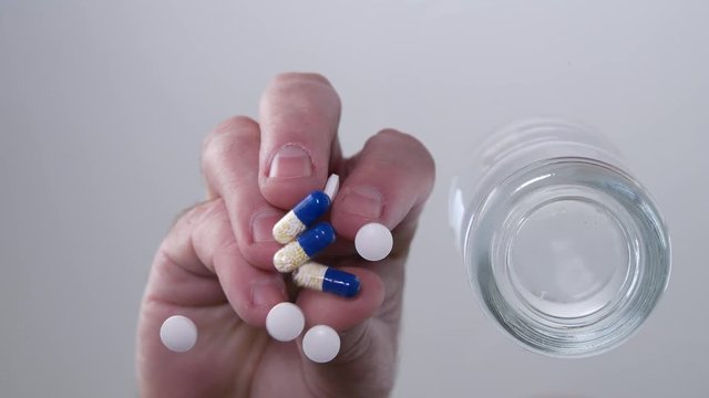 Image with Man Hands Putting some Medicine Pills On Table Glass Surface