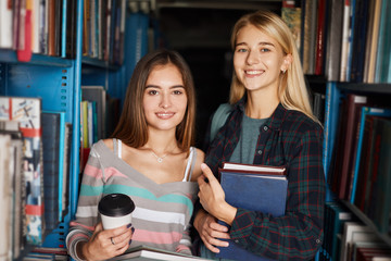 Couple of young female designers come to public library for new ideas, looking through the old magazines and annuals for inspiration.