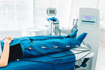 Cropped view of woman lying in massaging suit at the spa clinic for the treatment of pressure...