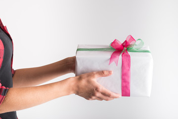 Woman holding paper wrapped gift box decorated with pink and green ribbons