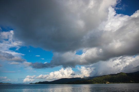 Grey storm clouds and still sea. Tropical island landscape. Rain season cloudscape. Typhoon clouds above still sea