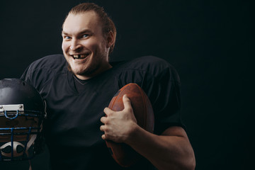 Satisfied cheerful handsome american caucasian man grins at camera, having his tooth knock out during a football match, but happy to win, isolated over black concrete background.