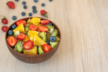 Healthy fresh fruit salad in bowl on light background. With copy space