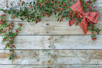 Fototapeta na wymiar Cristmas greetings postcard. Xmas card. tie and red berries with green foliage on wooden background. 