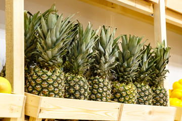 Pineapples and tangerines are on the shelf in the store
