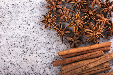 Cinnamon sticks and anise stars over stone background, top view