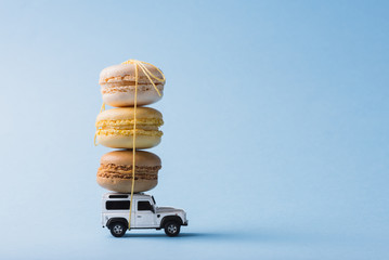 Macaron cookies on top of a toy car over blue background
