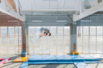 flexible guy doing flip over the mat in the sport center. full length side view shot. motivation....