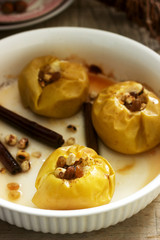 Baked apples with raisins, hazelnuts and cinnamon on wooden background. Rustic style.