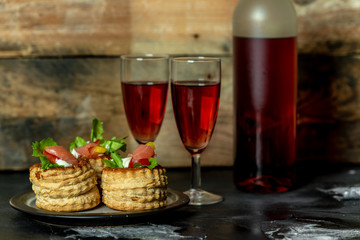 French cuisine, crunchy patties with lettuce and smoked salmon on a wooden, rustic background, next to a glass of red wine