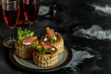 French cuisine, crunchy patties with lettuce and smoked salmon on a dark, rustic background, next to a glass of red wine