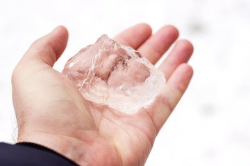 I female hand with a handful of fresh fallen snow, against snowy background