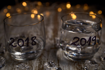 an almost empty glass of the year 2018 and another full of the new year 2019