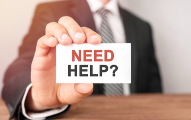 Obraz premium Businessman holding a card with text NEED HELP
