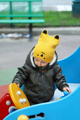 Baby With A Funny Yellow Hat And A Winter Jacket