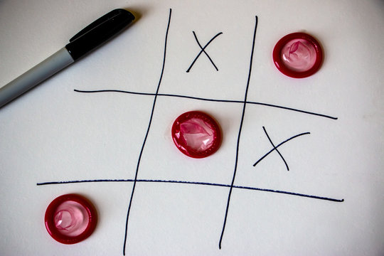 Closeup photo of the condoms as O symbol on Tic Tac Toe game board. Male condoms are also an effective way to prevent pregnancy.