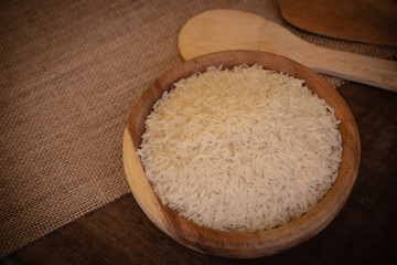 Fototapeta na wymiar Uncooked Jasmine rice in wooden bowl on the table. Jasmine rice has a subtle floral aroma and a soft, sticky texture when cooked. 